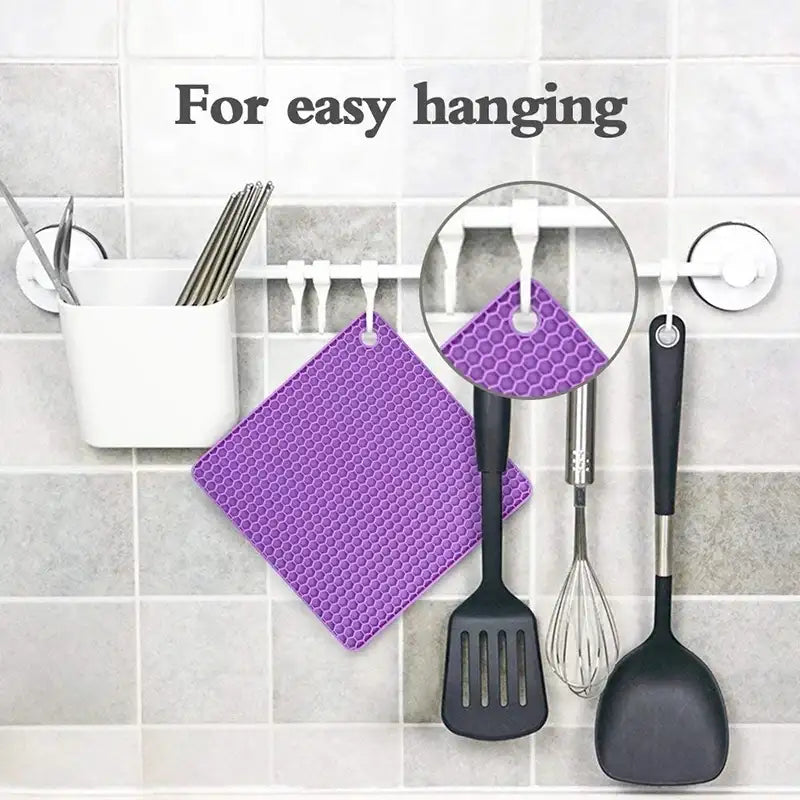 Purple honeycomb patterned pot holder hanging on a hook with kitchen utensils on a tiled wall.