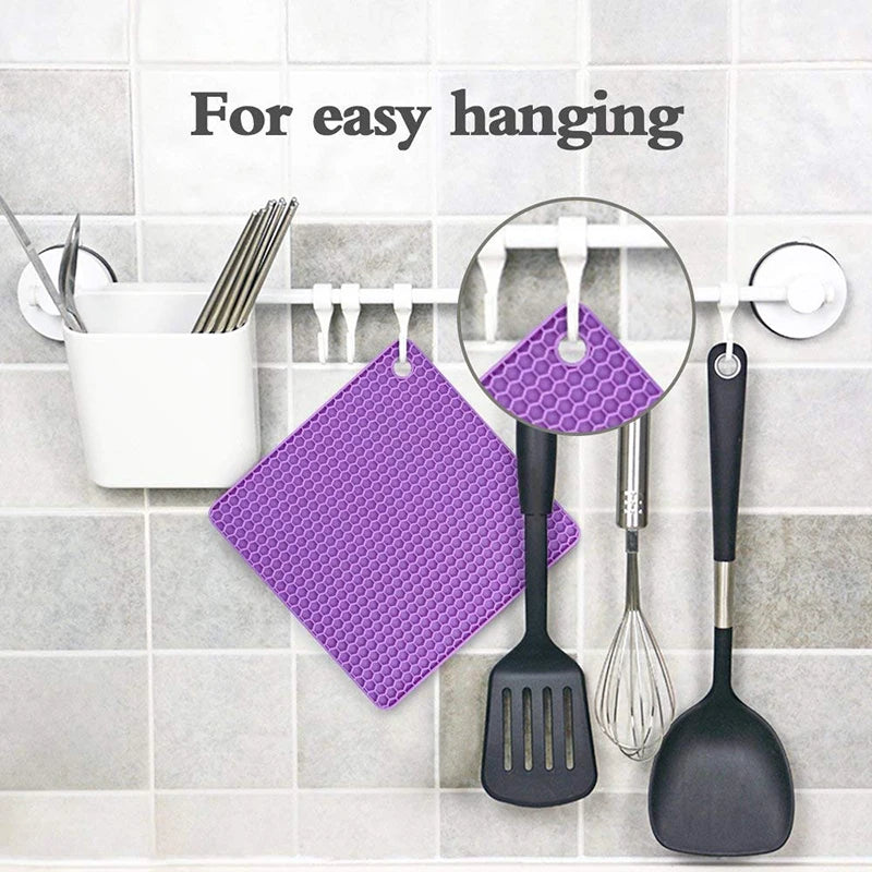 Purple honeycomb patterned pot holder hanging on a hook with kitchen utensils on a tiled wall.