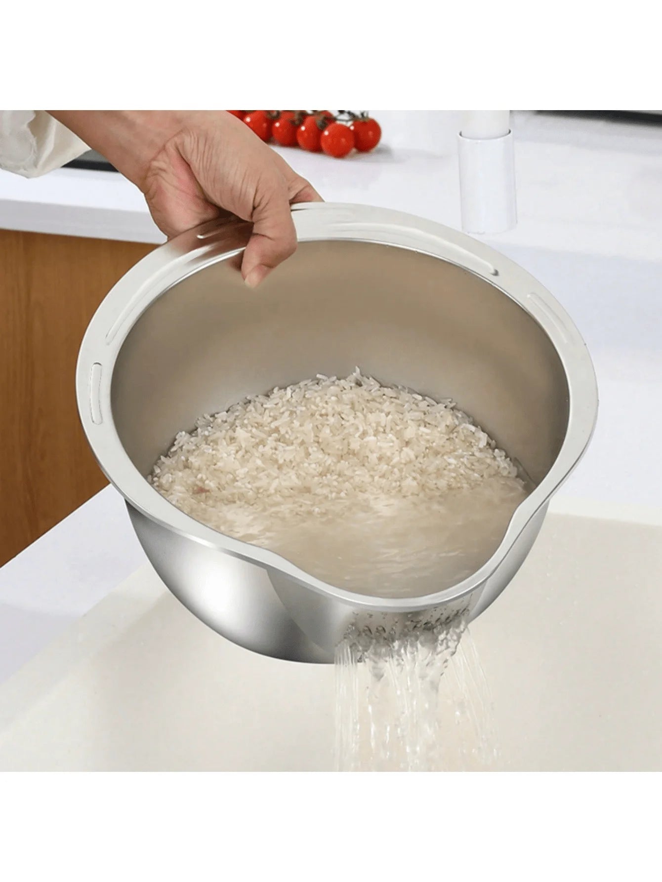 Stainless steel colander with rice being poured into it on a white surface.