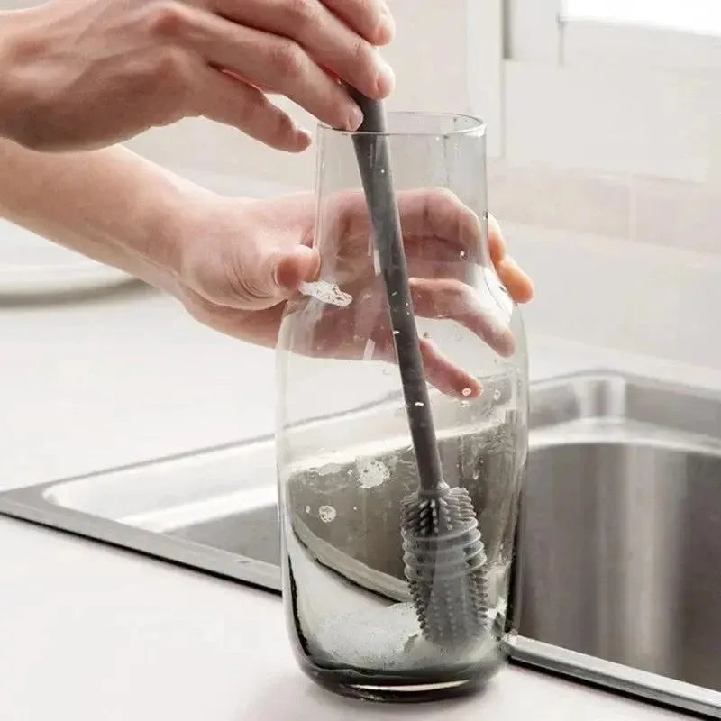 Person cleaning a glass with a brush in a kitchen setting