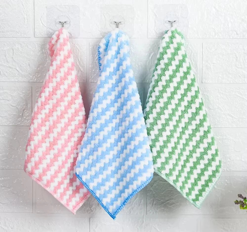 Three checkered towels in pink, blue, and green hanging on a white wooden surface.