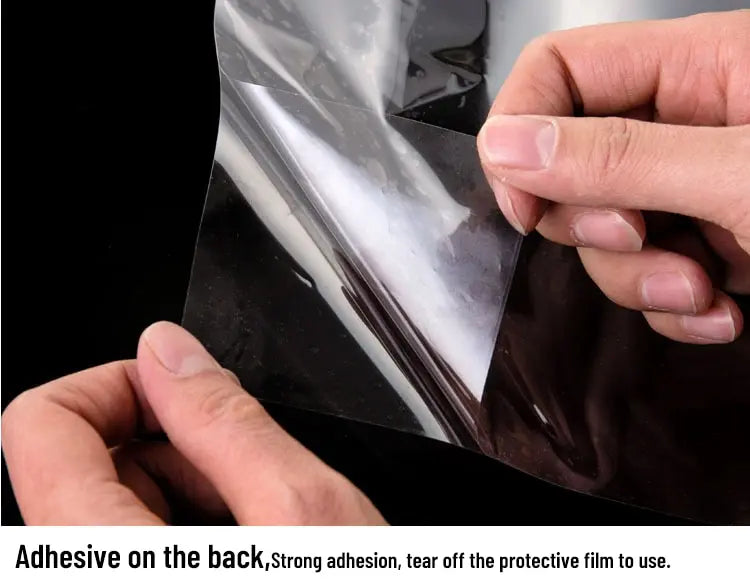 Person peeling back a protective film from a car window film.