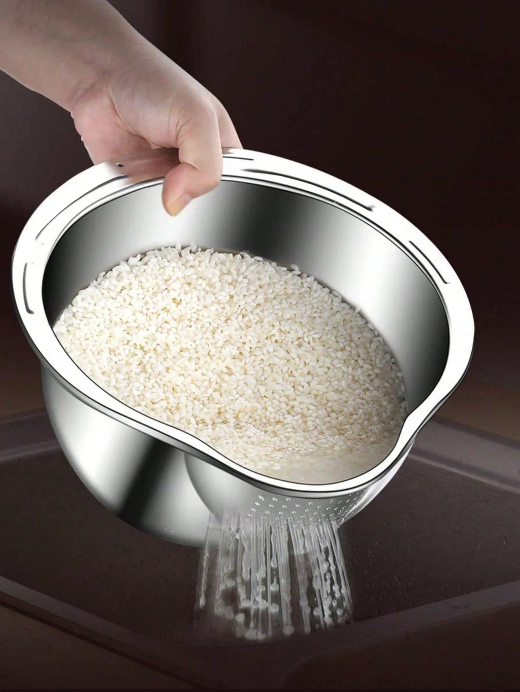 Hand pouring rice from a metal colander onto a dark surface