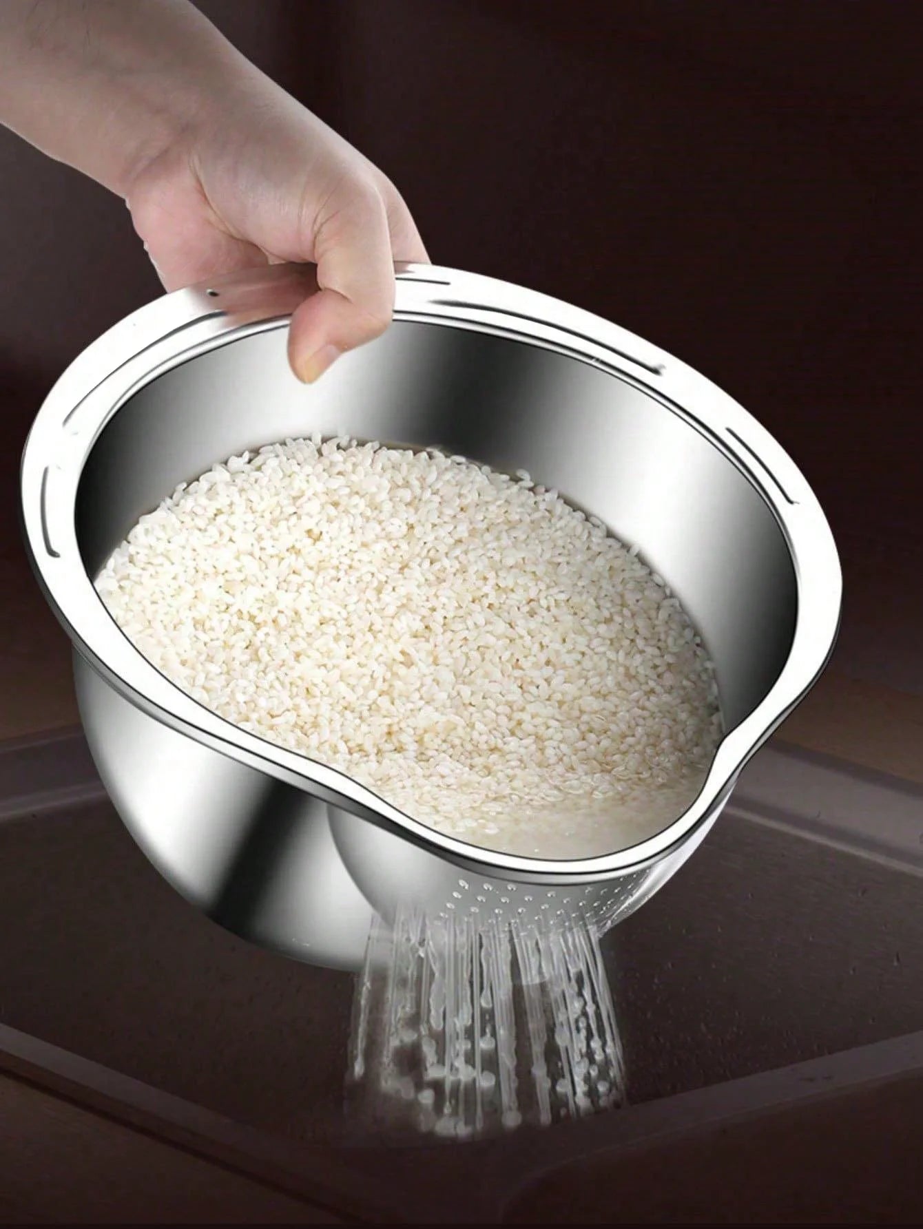 Hand pouring rice from a metal colander onto a dark surface
