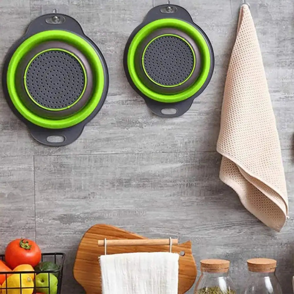 Collapsible colanders with green interior and gray exterior on a kitchen wall.