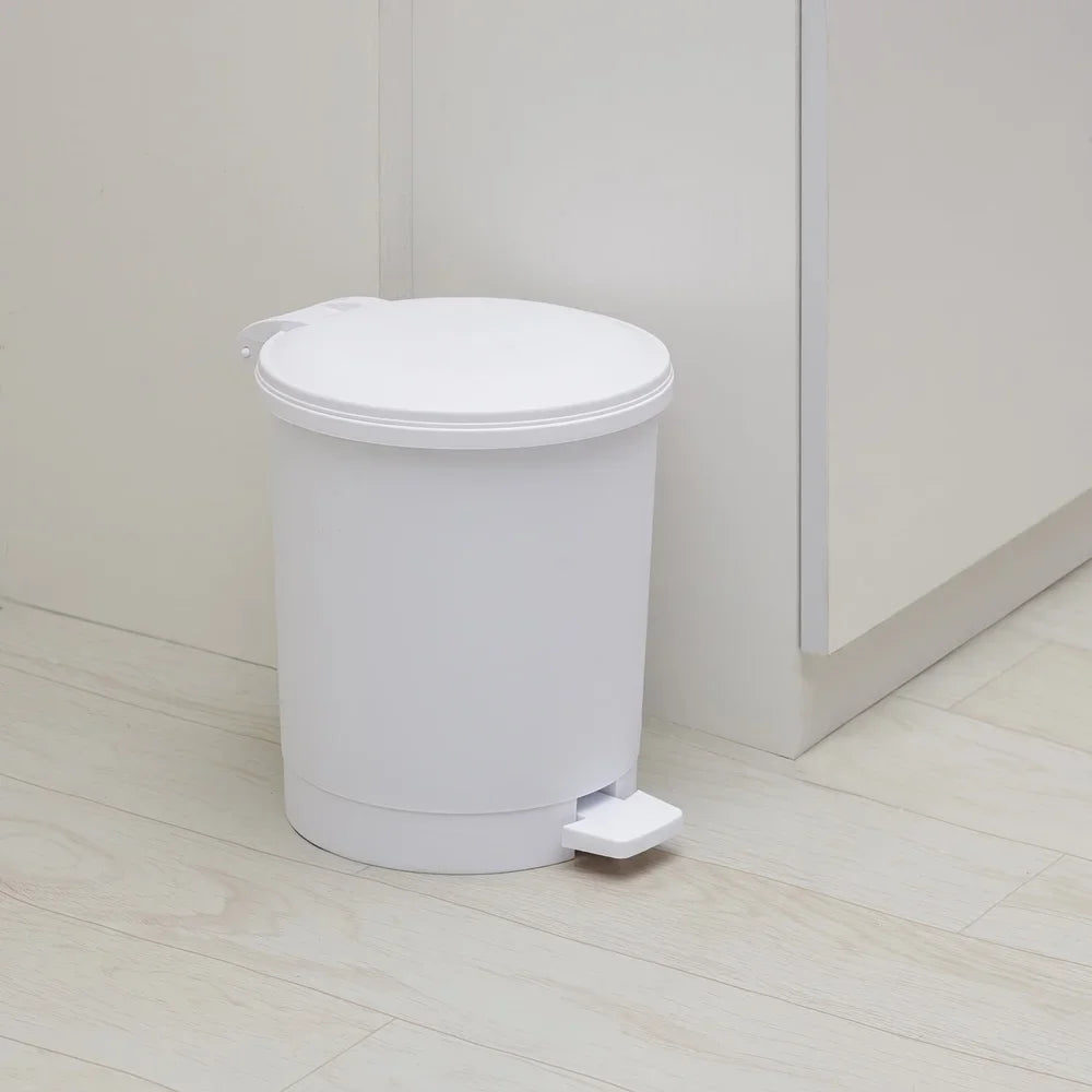White trash bin with foot pedal on a light wooden floor.
