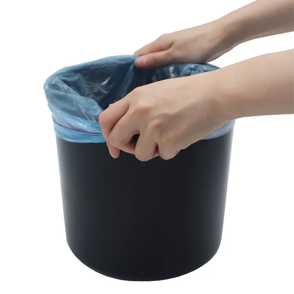 Person putting a blue trash bag into a black trash can on a white background