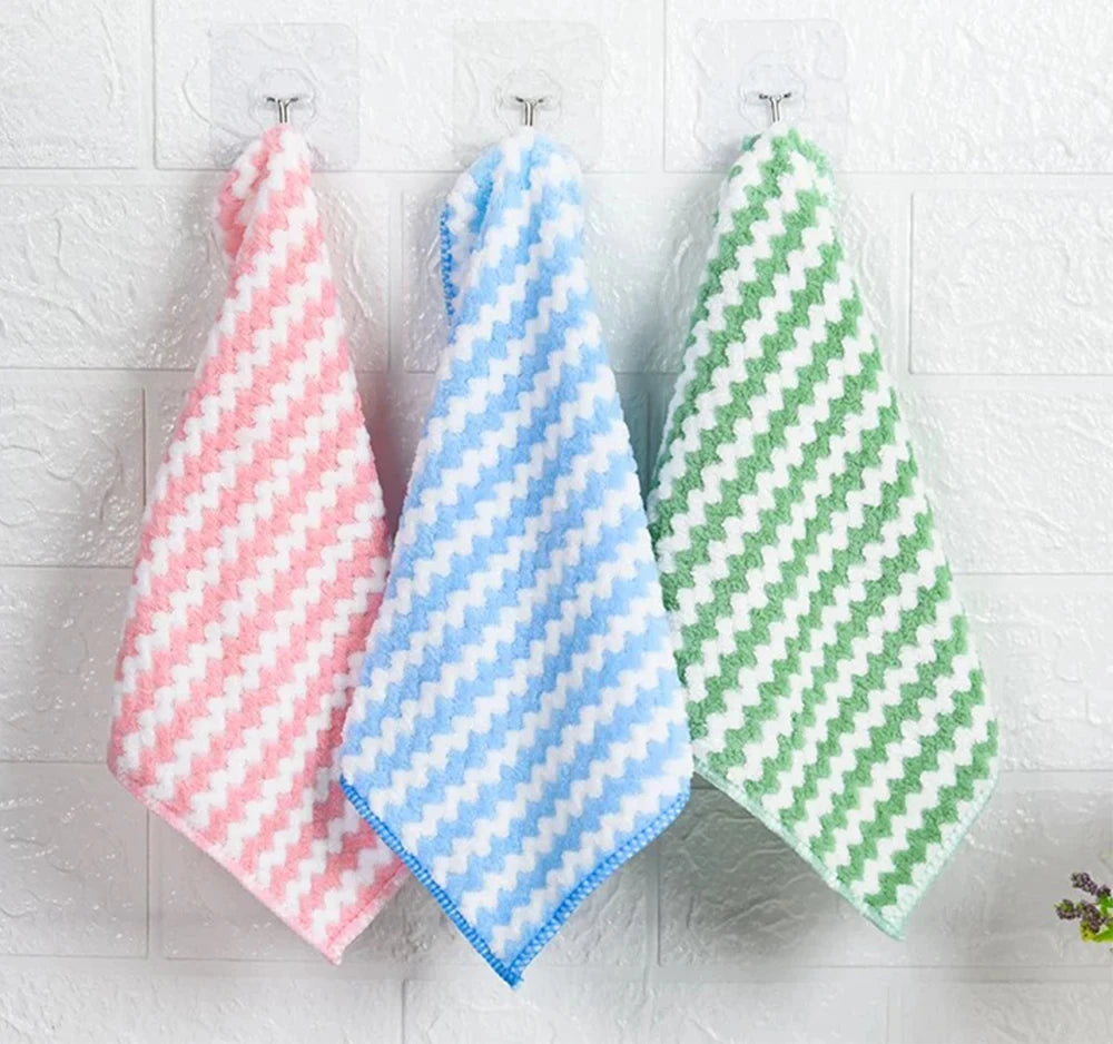 Three checkered towels in pink, blue, and green hanging on a white wooden surface.