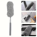Gray feather duster with a telescopic handle on a white background, used for cleaning various surfaces.