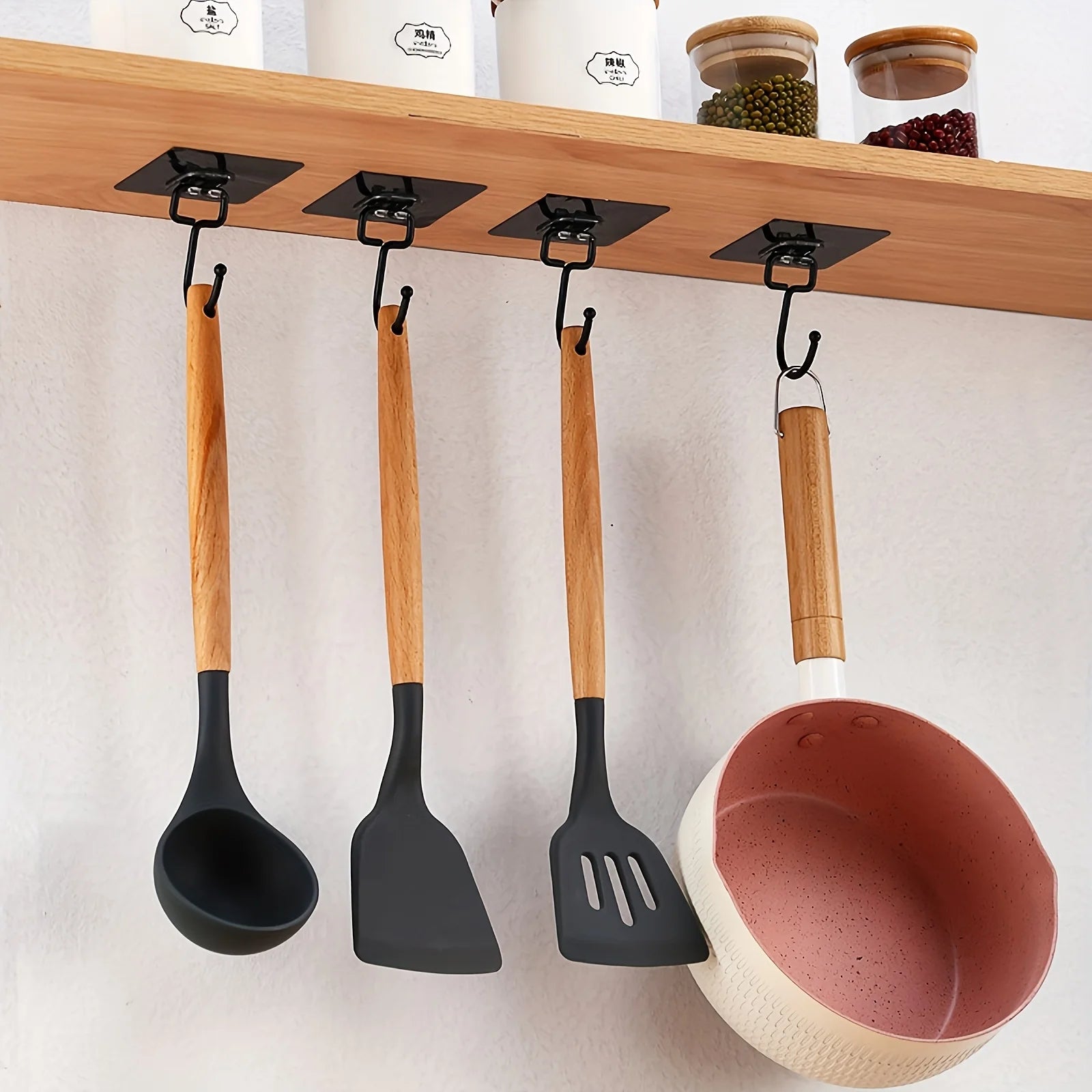 Set of kitchen utensils with wooden handles hanging on a wooden shelf.