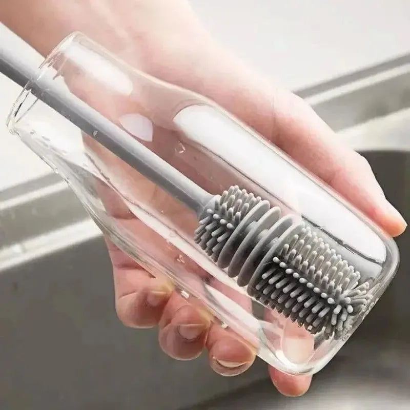 Hand holding a clear plastic case with a gray bristle brush inside, against a neutral background.