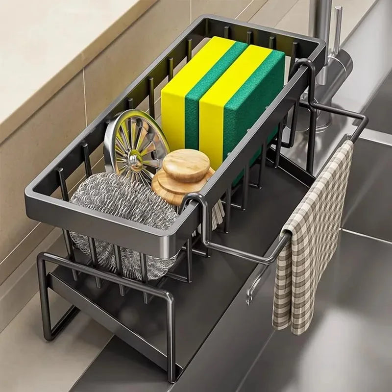 Dish drying rack with sponges, scrubber, and towel on a kitchen counter.