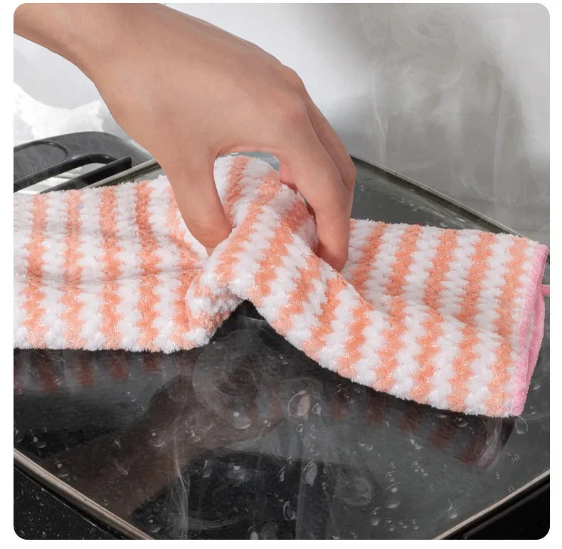 Hand using a striped pink and white cloth to clean a glass surface.
