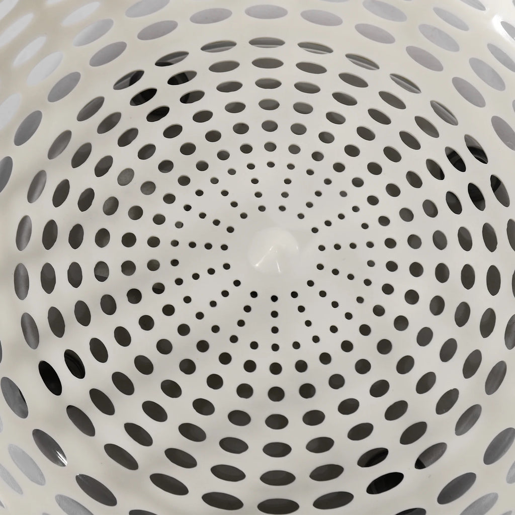 Close-up of the inside of a white plastic basket or colander with a circular pattern of perforated holes.