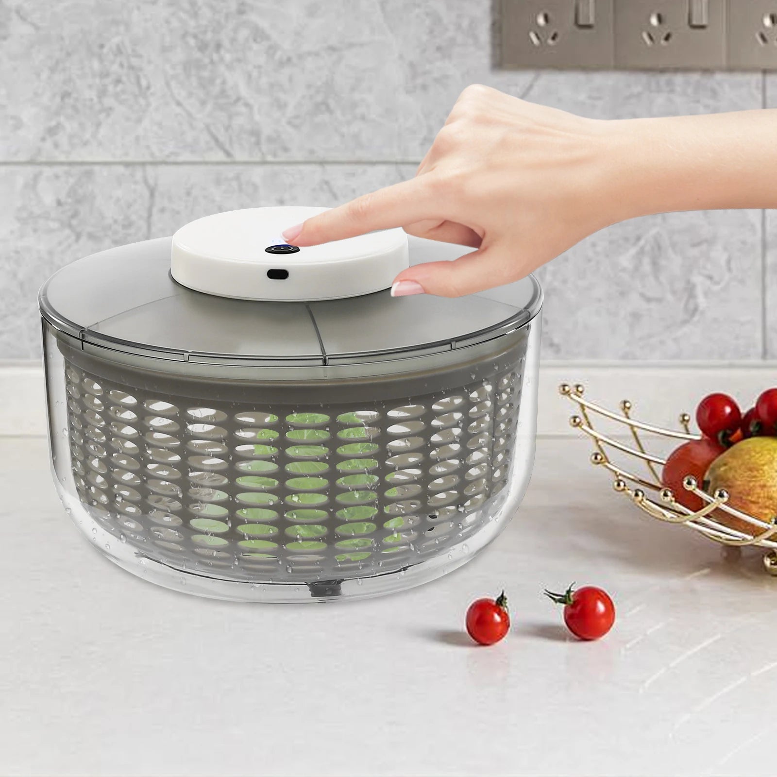 Salad spinner with a hand pressing a button on a kitchen counter.