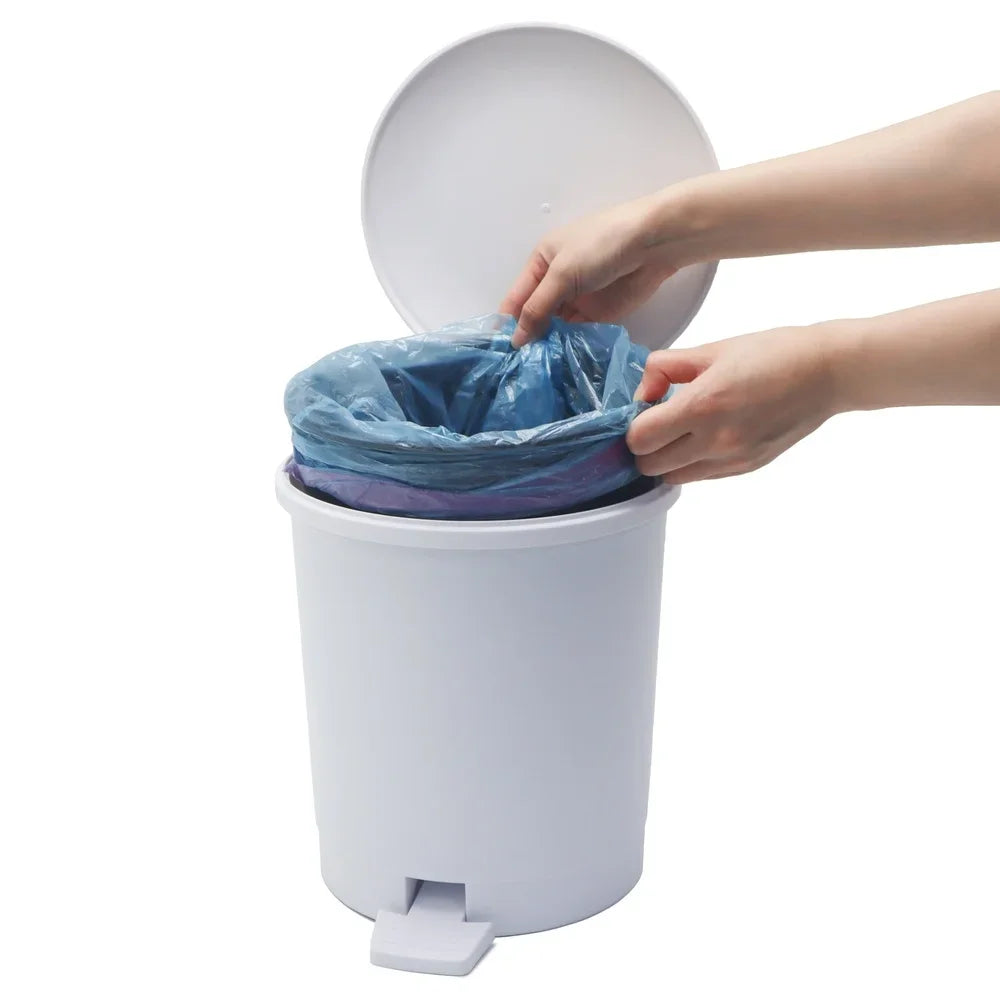 Person putting a trash bag into a white trash can with a foot pedal on a white background