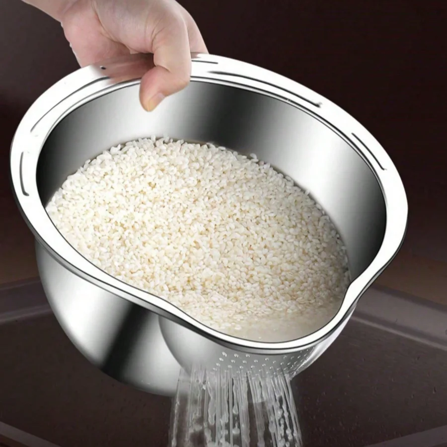 Stainless steel rice strainer with rice being poured into it on a dark background