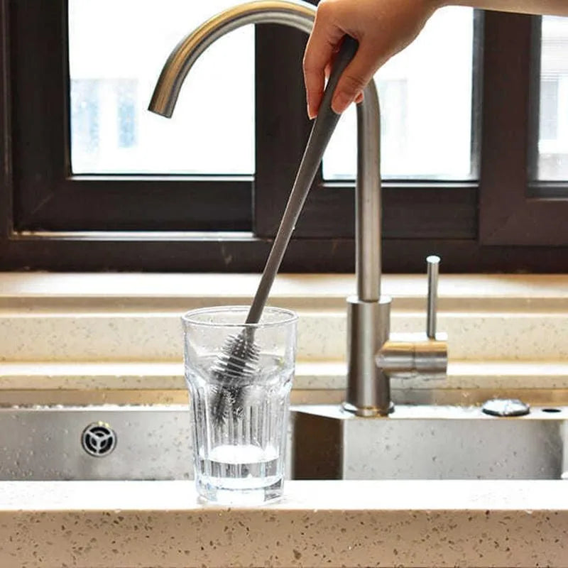 Person using a water filter straw to drink from a glass in a kitchen sink.