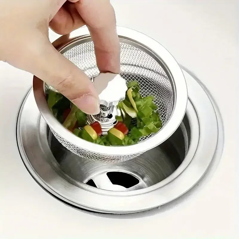 Hand using a small mesh strainer to collect vegetables over a sink drain.