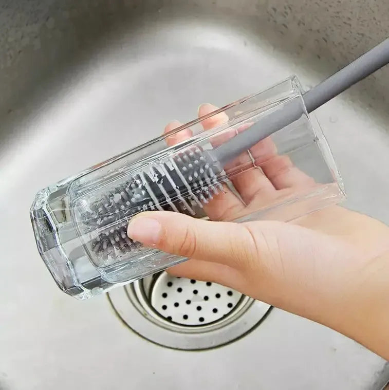Clear kitchen brush with gray handle held over a sink