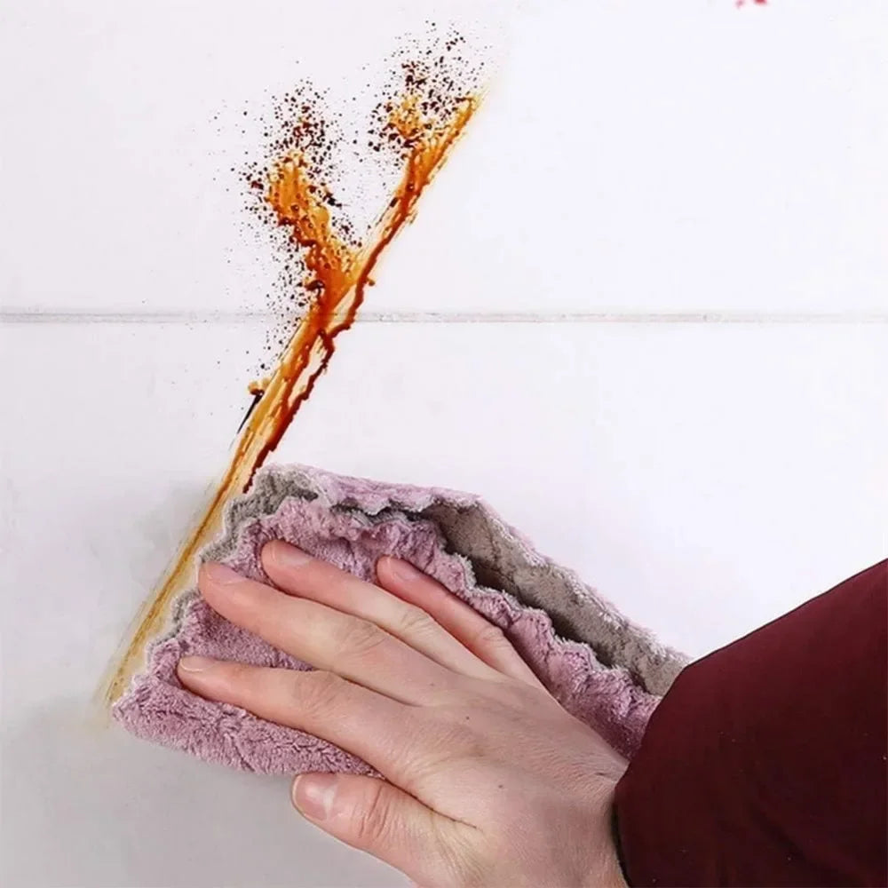 Hand using a pink cloth to clean a brown stain on a white surface