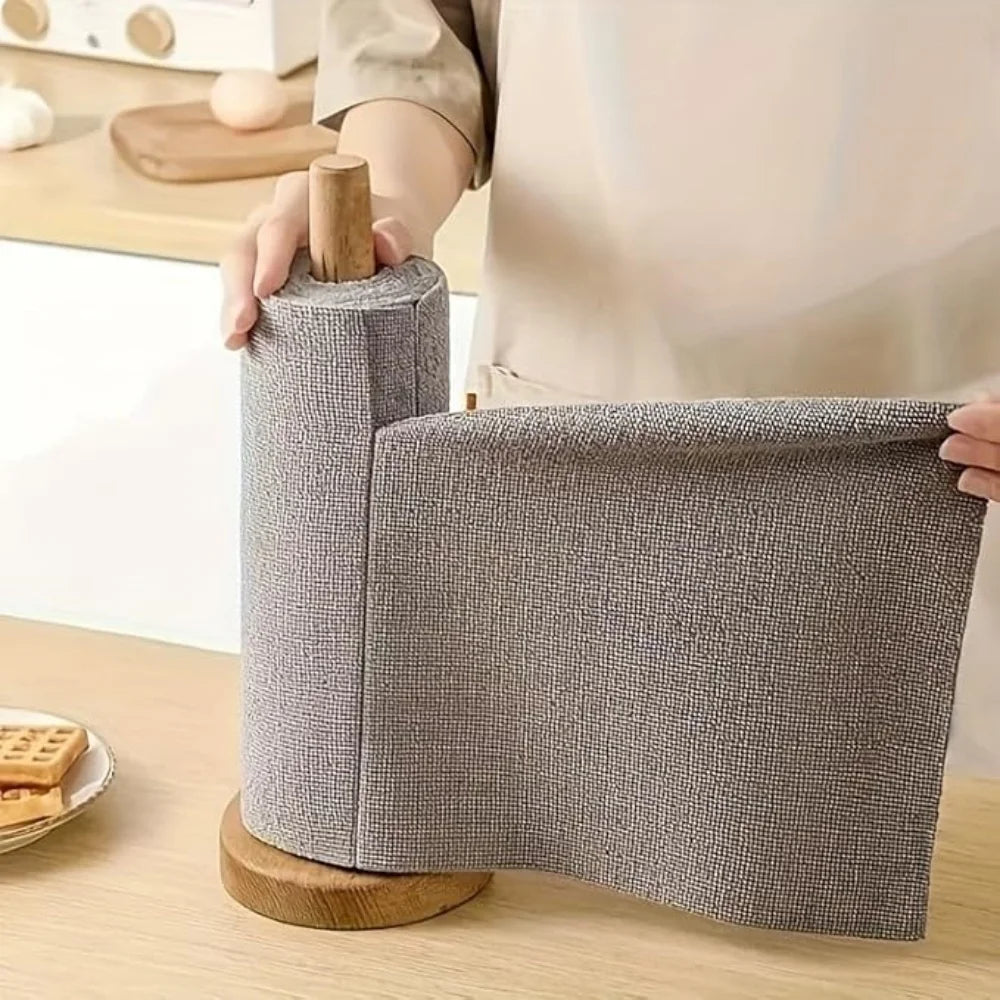 Person unrolling a roll of gray fabric on a wooden surface with a blurred background
