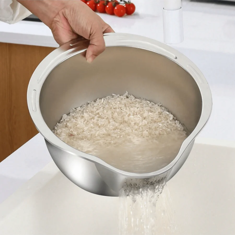 Person using a metal rice cooker with rice being poured out on a kitchen counter.